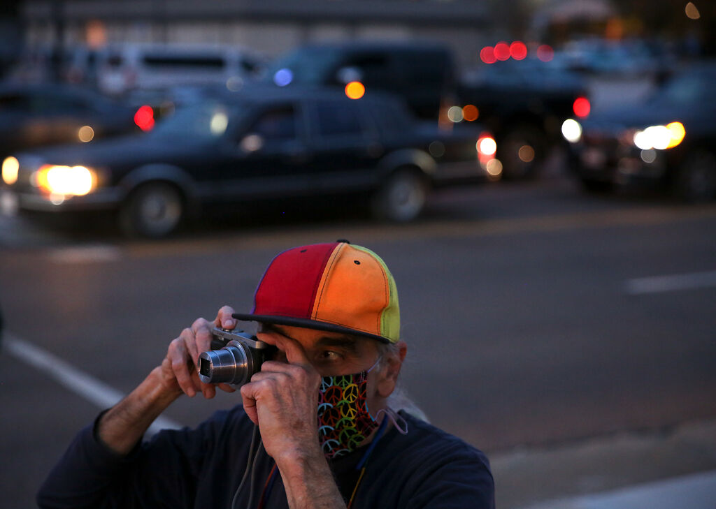 Director of Mid-Missouri Peaceworks Mark Haim raises a camera to his eye during a demonstration on Wednesday at the intersection of Broadway Blvd. and Providence Rd. in Columbia.